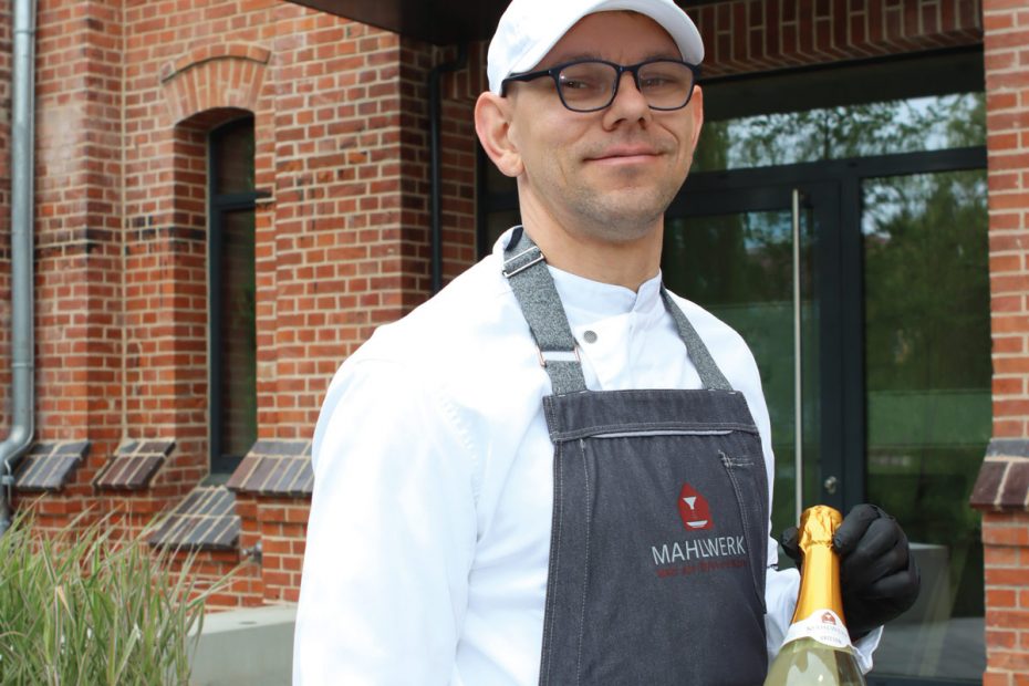 Dirk Lewerenz mit einer Flasche 800 Jahre Parchim Jubiäumssekt vor dem MAHLWERK