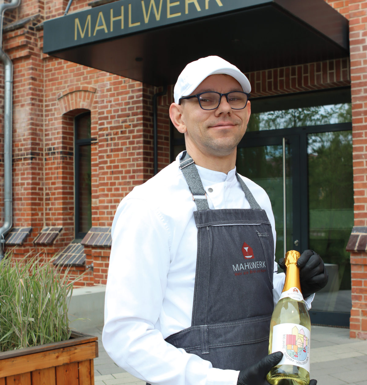 Dirk Lewerenz mit einer Flasche 800 Jahre Parchim Jubiäumssekt vor dem MAHLWERK